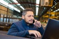 warehouse manager using telephone and laptop in large warehouse Royalty Free Stock Photo