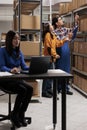 Warehouse managers picking order and taking parcel from shelf