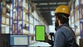 Warehouse operator holds greenscreen on tablet