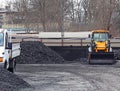 Warehouse for retail sale of coal to the population with a loading excavator of yellow color.Trade in natural resources and minera