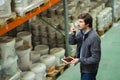 Warehouse storeman holding digital tablet and talking into walkie-talkie