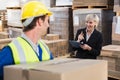 Warehouse worker holding box with manager behind him Royalty Free Stock Photo