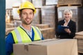 Warehouse worker holding box with manager behind him Royalty Free Stock Photo