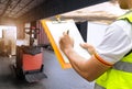 Warehouse worker holding clipboard checking on checklist for loading shipment goods into container truck. Royalty Free Stock Photo