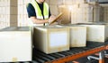 Warehouse worker holding clipboard writing on paper for delivery shipment boxes.