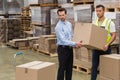Warehouse worker and manager carrying a box together Royalty Free Stock Photo