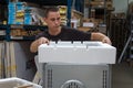 Warehouse worker packs oven in special material for shipment to buyer