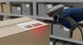 Warehouse Worker Scanning Barcode on Cardboard Box in Industrial Setting with Organized Shelves in the Background Royalty Free Stock Photo