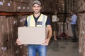 Warehouse worker smiling at camera carrying a box Royalty Free Stock Photo