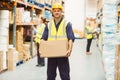 Warehouse worker smiling at camera carrying a box Royalty Free Stock Photo