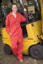 Warehouse worker standing by forklift