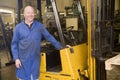 Warehouse worker standing by forklift