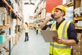 Warehouse worker talking on the phone holding clipboard