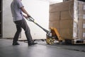 Warehouse worker unloading cargo pallet out of the inside container truck. Shipment boxes. Delivery service.