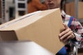 Warehouse worker using wheelchair while holding cardboard box Royalty Free Stock Photo