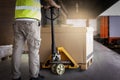 Warehouse worker working with hand pallet truck loading heavy boxes on pallet into cargo container. Shipment, Delivery sevice. Royalty Free Stock Photo