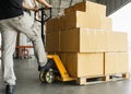 Warehouse worker working with hand pallet truck unloading shipment goods at warehouse