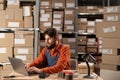 Warehouse worker in workwear working on laptop at storage compartment. Royalty Free Stock Photo