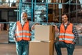 handsome middle aged warehouse workers standing with boxes and smiling Royalty Free Stock Photo