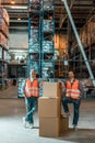 male warehouse workers in vests standing with boxes and smiling Royalty Free Stock Photo