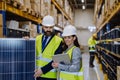Warehouse workers checking stuff in warehouse with digital system in tablet, holding solar panel. Royalty Free Stock Photo