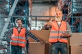 cheerful warehouse workers with digital tablet smiling at camera and showing