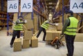 Warehouse workers loading boxes with pallet trolley among high shelving racks Royalty Free Stock Photo