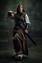 Full-length portrait of seriuos beautiful woman in image of medieval warrior or knight with dirty wounded face with big Royalty Free Stock Photo