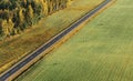 Warm aeriel view of autumn morning over straight black road with electricity line, forest and agricultural field