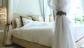 Warm atmosphere around bedroom in resort style hotel with white bedsheet, set of pillows on bed