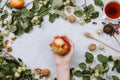 Warm autumn flatlay with apple branches, fruits, walnuts, red tea in a cup and woman`s hand