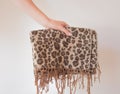 Warm autumn winter leopard scarf with fringe in the hands of a young woman. Large wide leopard print scarf Royalty Free Stock Photo