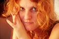 Warm beautiful sensual portrait in close-up of a young sexy woman redhead with long curly hair indoor Royalty Free Stock Photo