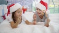 Warm Christmas atmosphere in which joyful sister and brother playing with candy canes, imitating a swordfight. Sister`s