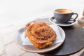 Warm cinnamon bun with icing sugar with cup of coffee