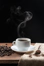 Warm coffe smoke, with .coffee beans. wooden spoon with coffe on wooden base, on dark background