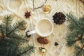 Warm coffee in stylish cup, anise star, fir branches, ornaments, pine cones and warm lights on cozy knitted background. Top view.