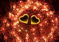 A warm color light garland surrounding two hearts. valentine`s day