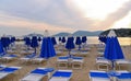 Warm colorful sunset on empty beach with blue chaise longues and calm sea water with old castle in background in Lerici, Liguria,