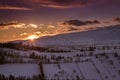 Warm and colorful sunset over Bran, a mountain village from Transylvania, covered with snow in wintertime