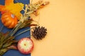 Warm and cool fall seasonal blue and yellow flatlay with festive pumkins, pine cones, and harvest plants for open concept and copy