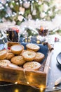 Warm cosy composition of traditional english festive pastry mince pies in wooden tray with blurred background of mulled wine