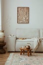 Warm and cozy living room with mock up poster frame, modern beige sofa, wooden oval coffee table, vase with dried flowers, round