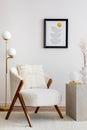 Warm and cozy living room with mock up poster, white armchair, lamp, consola and personal accessories. Beige wall. Home decor.