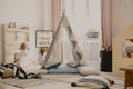 Warm and cozy scandinavian playroom with tent, pillows and toys, real photo