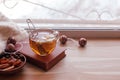 Warm and cozy window seat with cup of tea and stack of books and garland on wooden window sill, rustic style home decor, copy