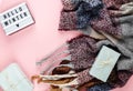 Warm, cozy winter clothing, scarf, lightbox on pastel pink background. hello winter title