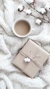 A warm cup of coffee sits beside a wrapped gift and an open book on a textured fabric surface, creating a serene Royalty Free Stock Photo
