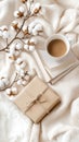 A warm cup of coffee sits beside a wrapped gift and an open book on a textured fabric surface, creating a serene Royalty Free Stock Photo