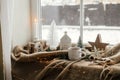 Warm cup of tea, christmas decor and lights on cozy blanket at window. Christmas Winter hygge